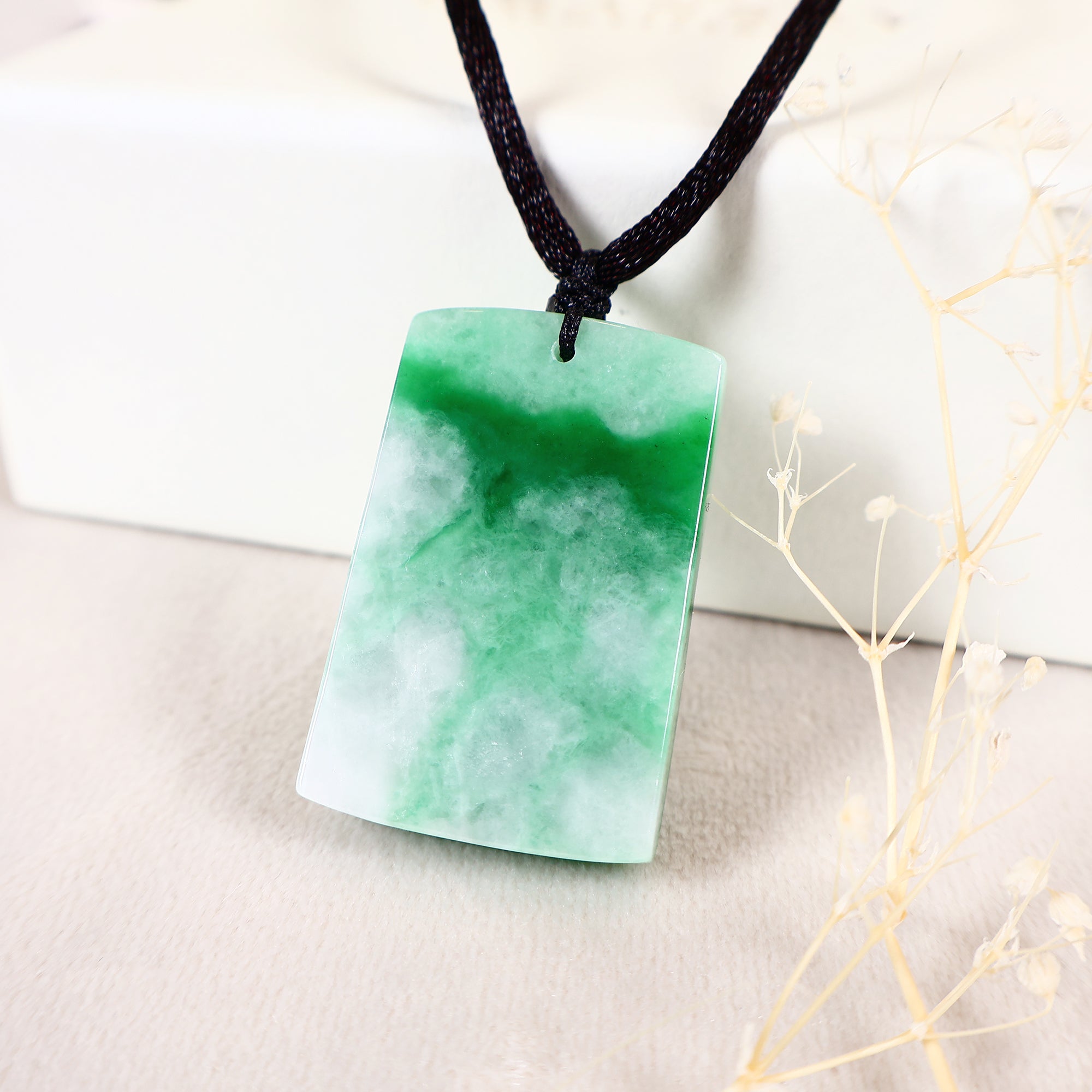 The back of a green rectangular jade pendant carved in the shape of a lotus